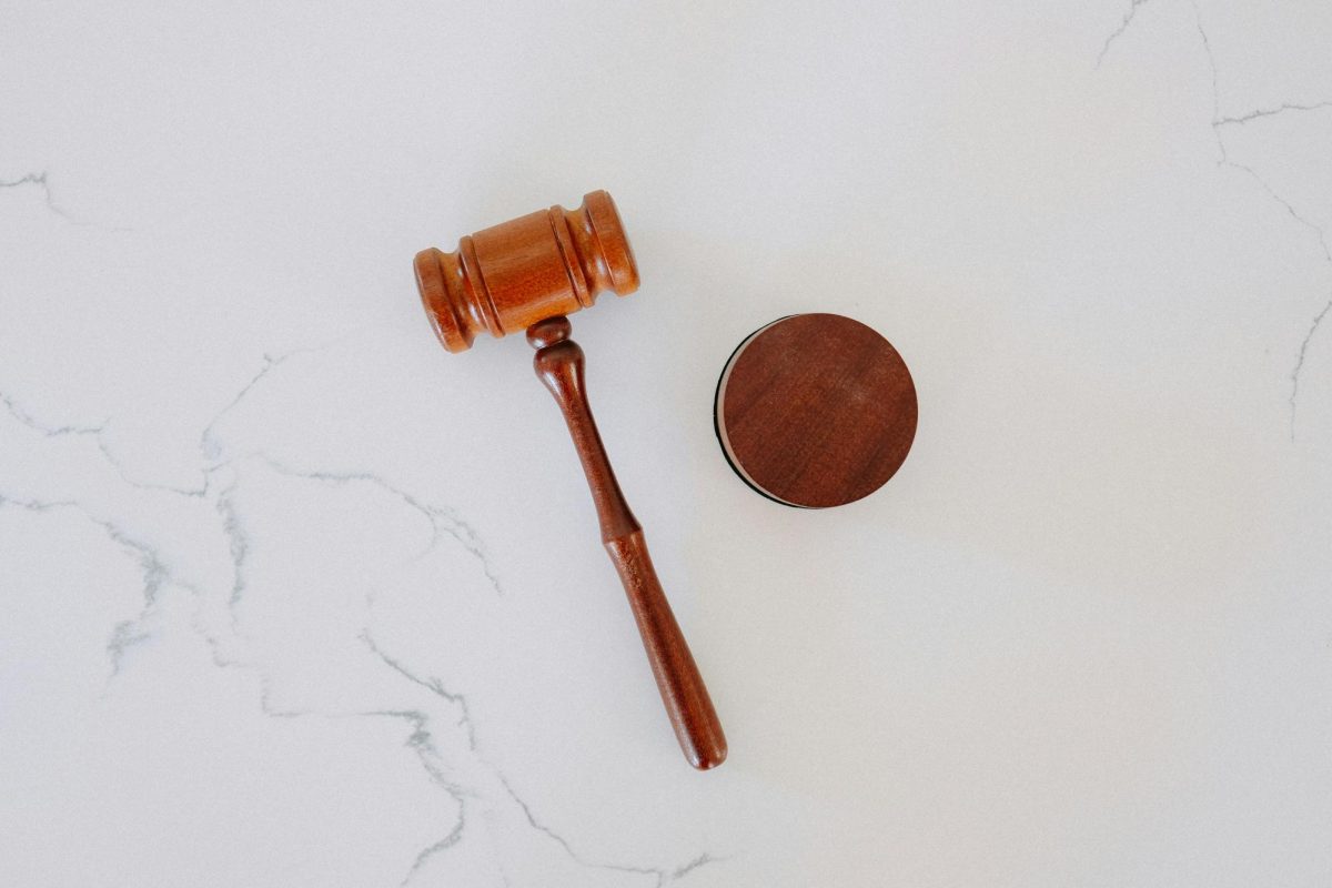 A gavel is displayed on a white marble backdrop.