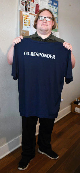 Martin Moore holds a “co-responder” shirt used by Pine Belt’s crisis response staff. He said the team tries to be on the scene within one hour after a call comes to them directly or through 988. If the caller is in a rural area, they try to arrive within two hours.