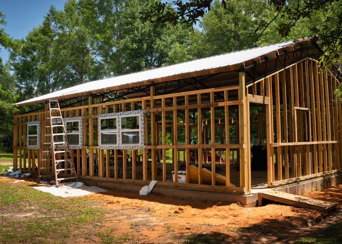 A single-story unfinished building with wooden framing, a metal roof and three windows on the left side.