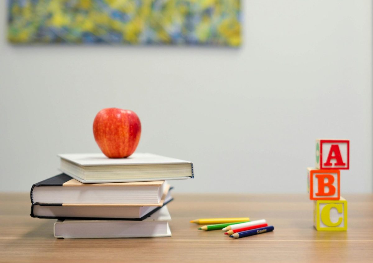 An apple sits on a stack of books beside blocks and pencils in this file photo.