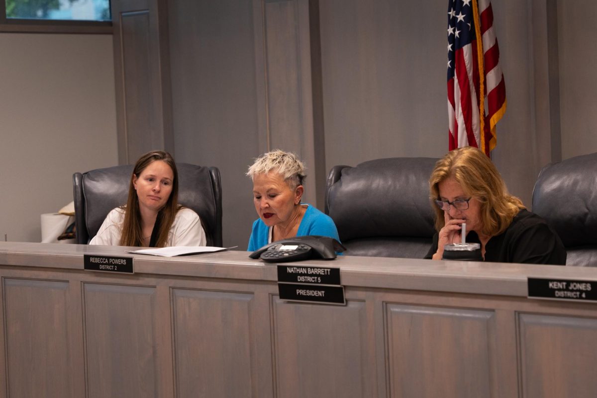 Three committee members seated behind a desk, including Dr. Jennifer Caldwell on the left, Jeannie Herrin in the center, and Dr. Karla Pope on the right, during a policy meeting.