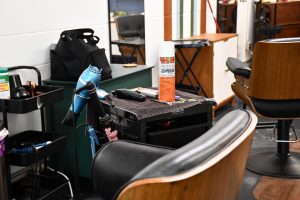 Wide view of a salon setup showing a styling chair, workstation, mirror, and disinfectant supplies in a training facility.
