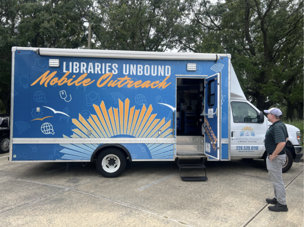 Sean Green stands next to mobile library van in parking lot.