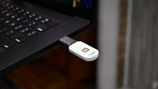 Close-up of a black and white USB device plugged into a black laptop.