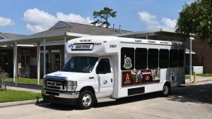 White transit bus labeled “Demand Response” is parked under a covered driveway outside the Hancock County Senior Center.