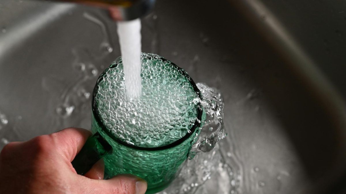 Water flows into a green glass at a kitchen sink in this file photo. In Long Beach, recent social media claims about dangerously high chlorine levels in the city’s tap water are not supported by five years of official water quality reports.