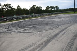 Concrete surface at Gulfport Dragway showing circular tire marks and burnout patterns.