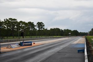 Wide-angle view of Gulfport Dragway’s drag strip extending into the distance with trees on either side.