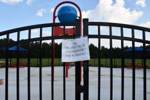 A close-up of a sign taped to the locked gate of the Richton splash pad that reads, “The splash pad is closed for the summer!!”