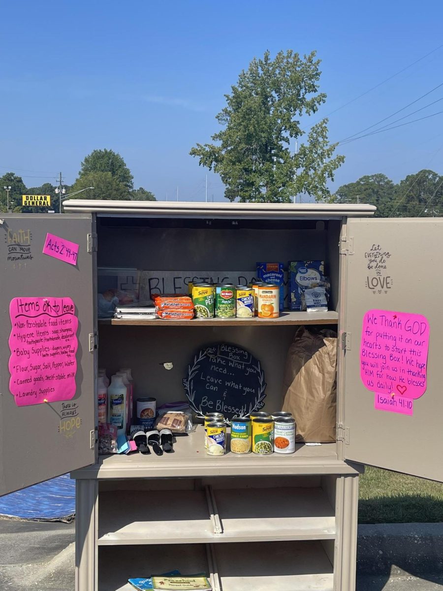 A tan cabinet filled with canned food, pasta and toiletries stands in a church parking lot in Hattiesburg.