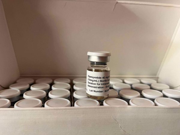 A small glass vial labeled “Elamipretide” sits among other vials in a box.