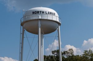 A water tower stands next to the North Lamar Water Association office building.
