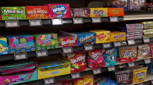 Boxes and bags of candy, including Skittles, M&M’s, Reese’s and Jolly Ranchers, arranged on a grocery shelf.
