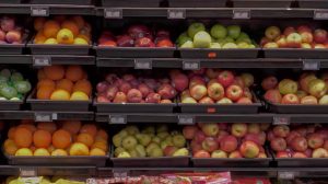 Colorful rows of apples, oranges and other fresh fruit displayed in black produce bins.