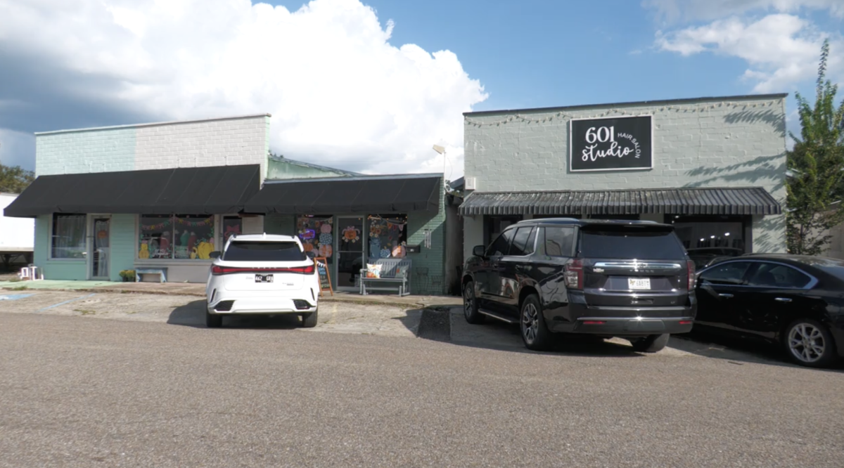 A storefront with black awnings and parked cars in front of MS Magnolia in Leakesville, Mississippi.