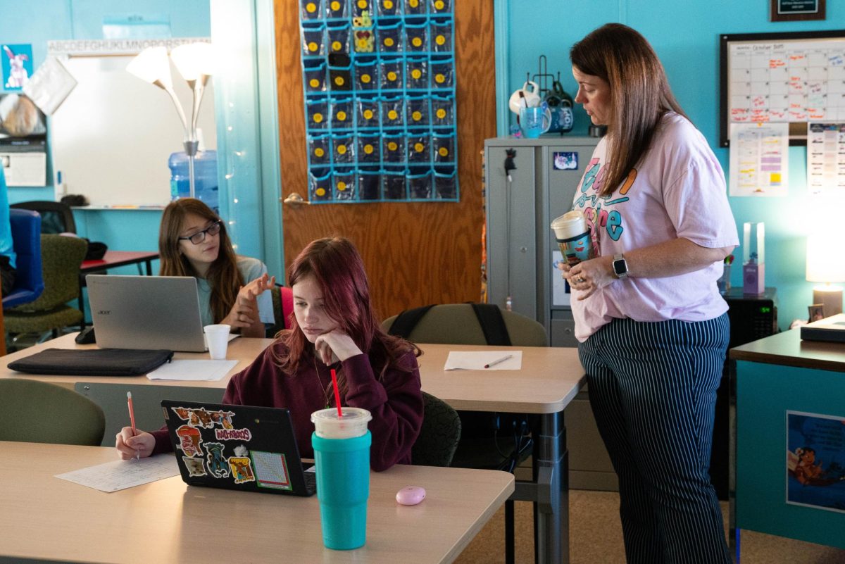 A teacher works one-on-one with a young student in a classroom.