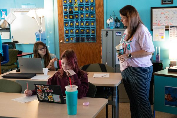 A teacher works one-on-one with a young student in a classroom.