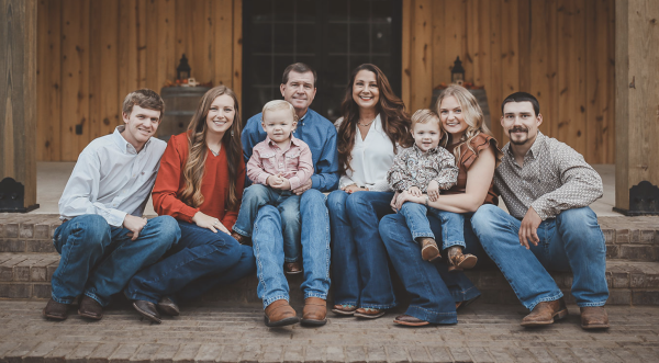 Eight members of the Seward family sit together on the front steps of their farm.
