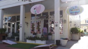 A person enters Dolce Bakeshop in downtown Long Beach, Mississippi, where colorful storefronts and signage attract tourists during Cruisin’ the Coast week.