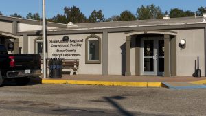 A beige building labeled “Stone County Regional Correctional Facility” and “Stone County Sheriff Department.” The structure has glass double doors and a covered entryway supported by square columns.