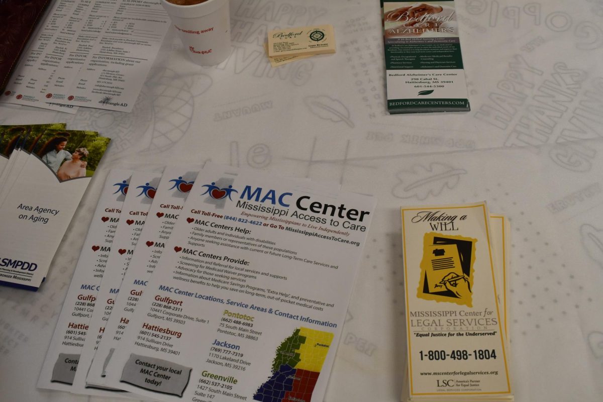 Brochures displayed on a white tablecloth include “Making a Will,” “Mississippi Access to Care,” “Bedford Care Alzheimers” and “Area Agency on Aging.”