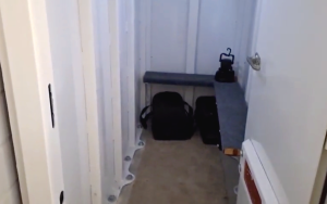 Inside view of a residential storm safe room with benches, bags and emergency supplies.