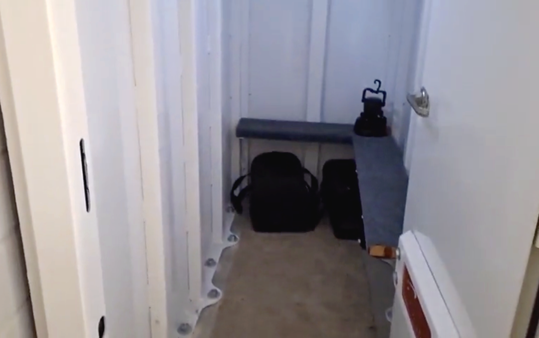 Inside view of a residential storm safe room with benches, bags and emergency supplies.