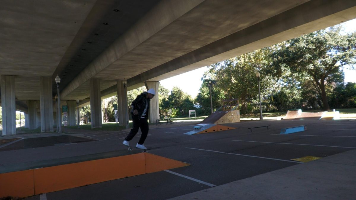 A person on a skateboard rides along a painted ledge at a DIY skatepark located under a concrete overpass in Biloxi, Mississippi.