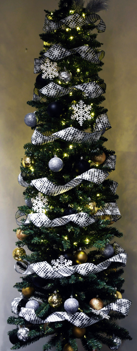 Artificial Christmas tree with warm white lights, black-and-white ribbon, snowflake decorations, and assorted gold, silver and black ornaments.