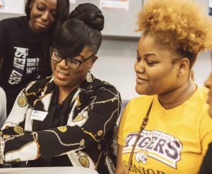 An instructor sits with students at a table.