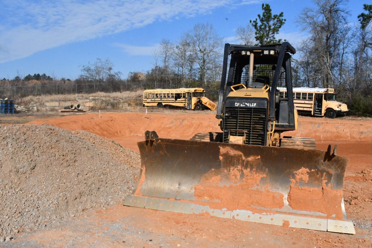 A bulldozer sits in front of a dirt area that has been leveled.