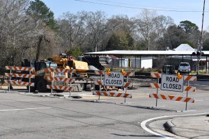 Orange and while road closed signs sit in front of a railroad crossing during a construction closure.