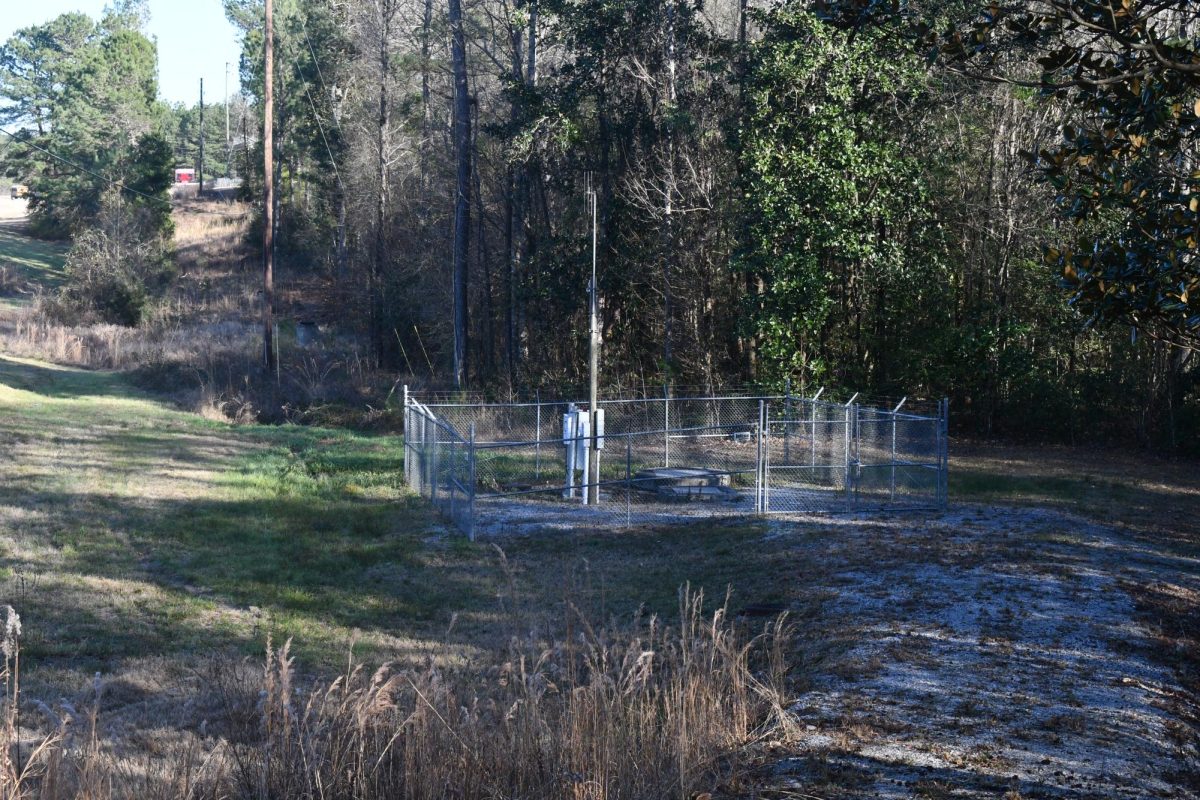 A fenced lift station facility with control equipment in a wooded area.