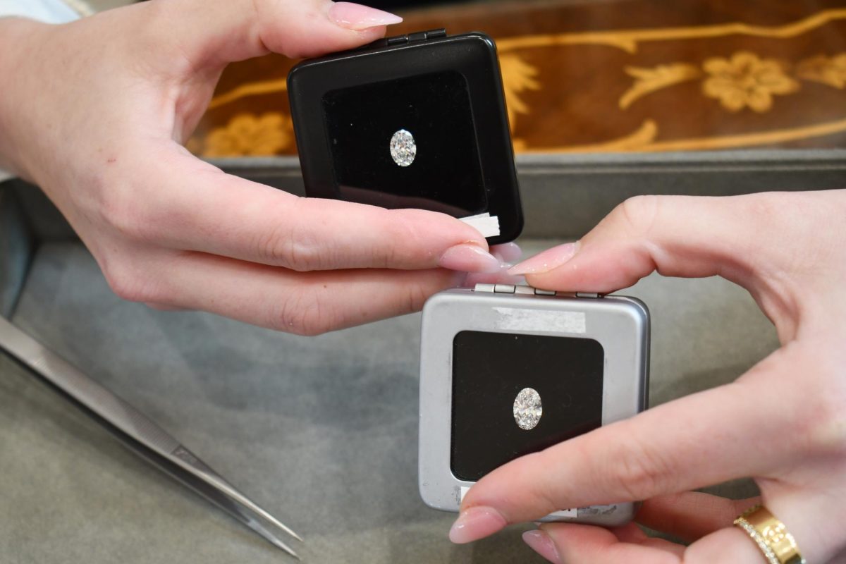 Two diamonds displayed in small cases, one in a black box and one in a gray box.