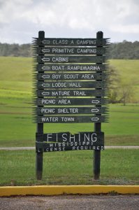 Wooden directional sign at Flint Creek Water Park listing camping areas, cabins, marina and other amenities.