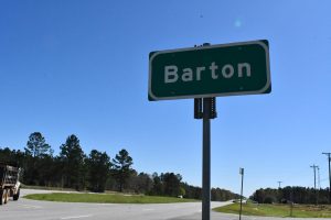 A green road sign reading “Barton” stands beside a highway in George County.