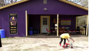A child rides a tricycle outside the purple Kamp Joy building.