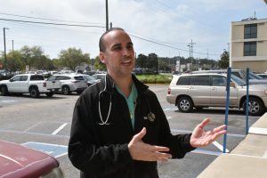 A man with a stethoscope around his neck gestures with his hands.