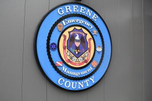 A blue Greene County Emergency Management logo is mounted on a gray wall.