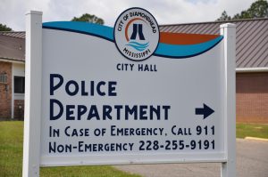A sign outside Diamondhead City Hall points to the police department and lists emergency and nonemergency phone numbers.