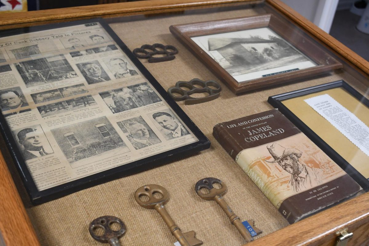 Old keys, brass knuckles, framed documents and a book about James Copeland are displayed in a museum case.