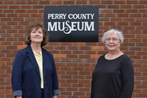 Two women stand outside in front of a sign reading “Perry County Museum.”