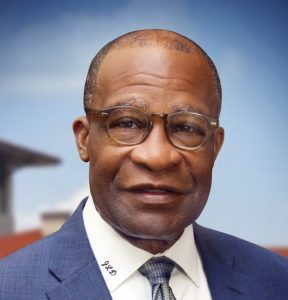 Sen. Johnny DuPree poses for a headshot in a blue suit and glasses against a blurred background.