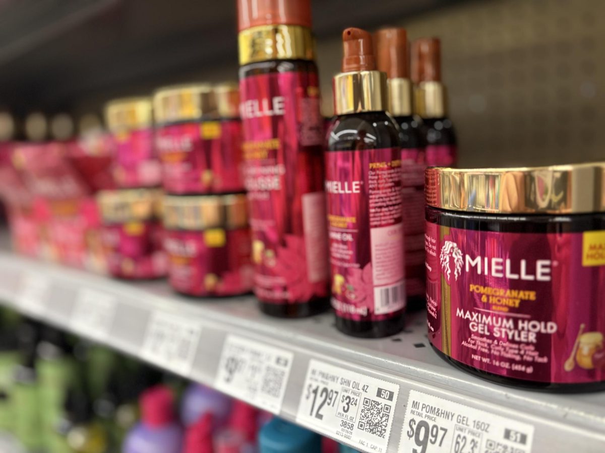 Mielle hair care products in red and gold containers sit on a store shelf with price tags below.