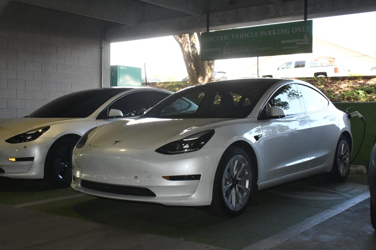 Two Tesla vehicles charge at a charging station in a parking garage at The University of Southern Mississippi. The photo illustrates a fact-check about the environmental and economic effects of electric vehicles.