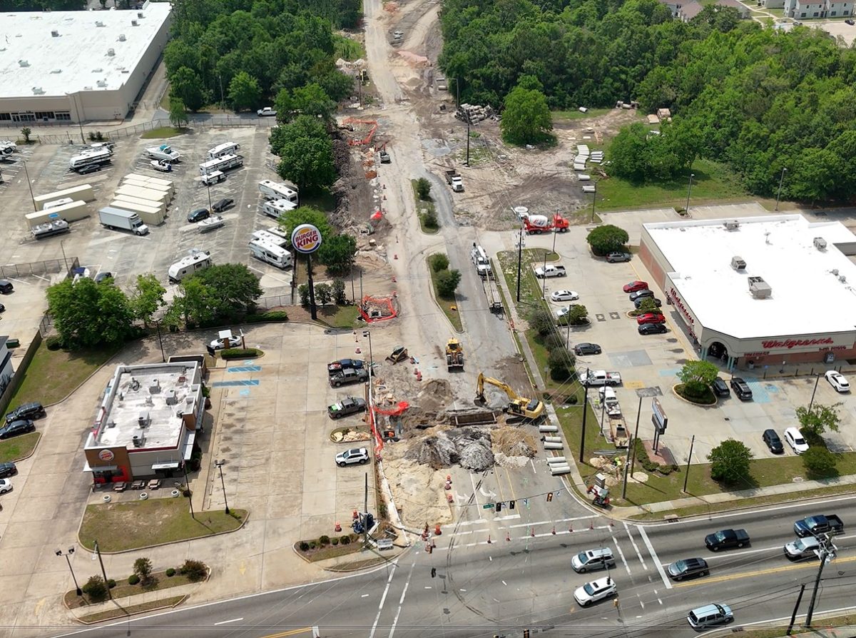 Aerial view of road construction on Popps Ferry Road in Biloxi, with construction equipment, traffic cones and nearby businesses visible.