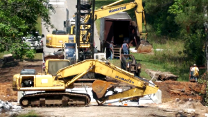 Construction equipment and workers are shown at a bridge replacement site along Old Highway 24 over Little Creek.