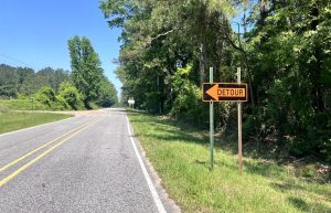 A roadside warning sign says a bridge is closed 4 miles ahead and access is limited to local traffic only.