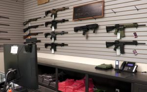 Several firearms hang on a wall inside a gun shop.