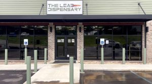 The exterior of The Lead Dispensary gun shop, with the store sign above the front doors.